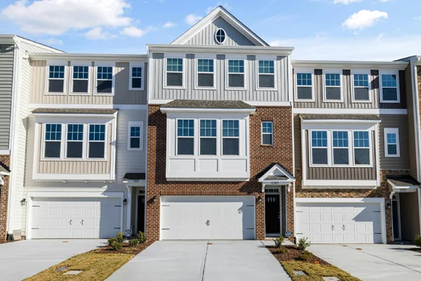 A row of 3 story townhomes with siding and brick each with a 2 car garage